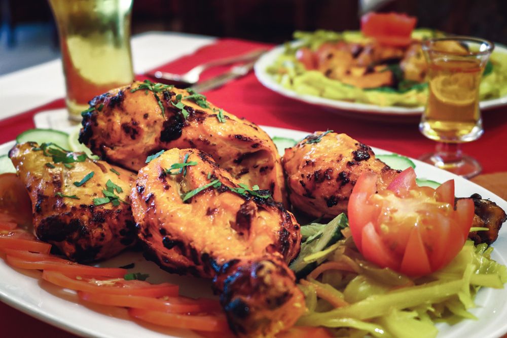 Gegrillte Tandoori-Hähnchenstücke mit Salat auf einem Teller